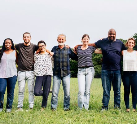 people standing in a line in a field smiling facing camera